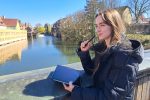 Frau blickt in die Ferne, hält in einer Hand ihr Tablet, in der anderen den Stift.